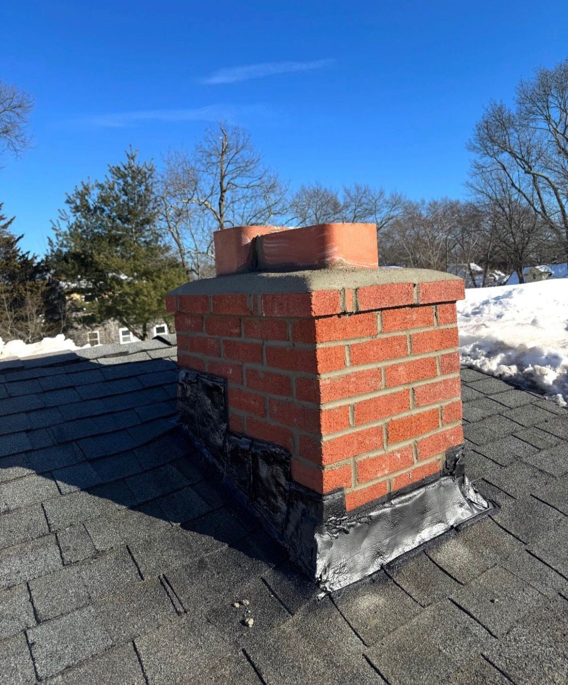 Red-brick chimney with a freshly rebuilt crown and new flashing after repair
