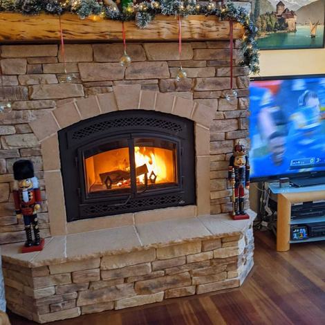 Traditional stone fireplace with an arched wood-burning insert and a live fire