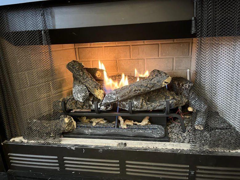Gas logs burning behind a mesh fireplace screen